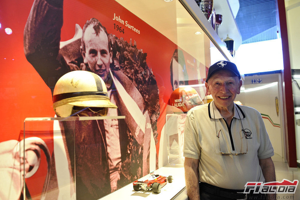 John Surtees junto al casco y el coche con el que ganó el título de 1964