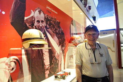 John Surtees junto al casco y el coche con el que ganó el título de 1964