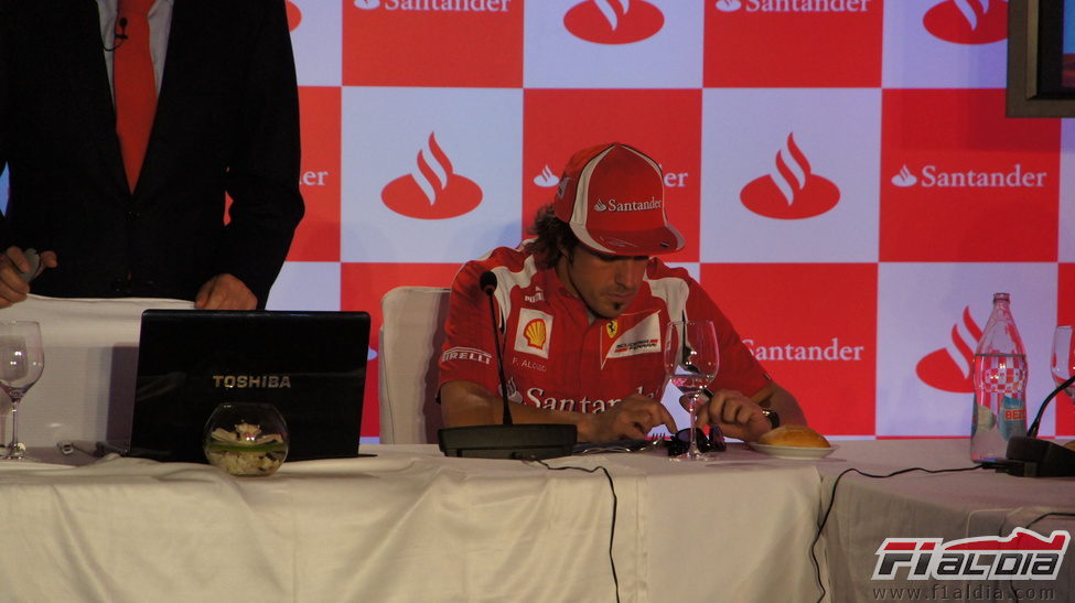 Fernando Alonso juega con su móvil durante el acto en el Jarama