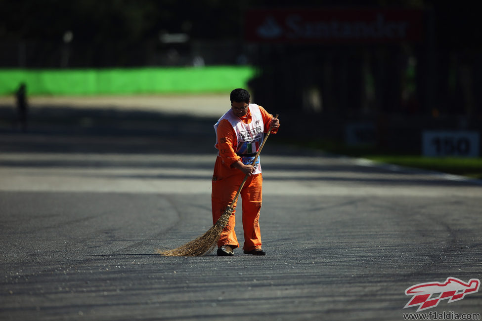 Un comisario quita los restos de suciedad de la pista